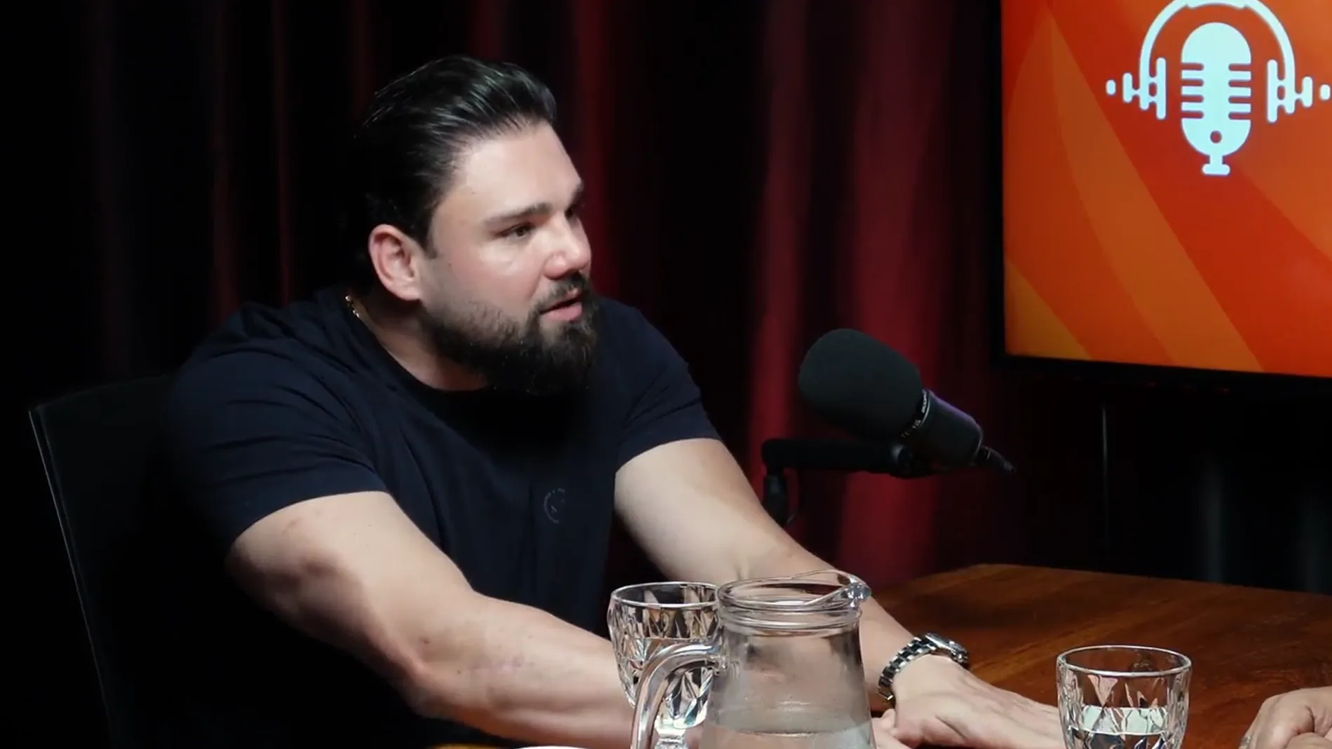 Participante em podcast com mesa e iluminação de fundo